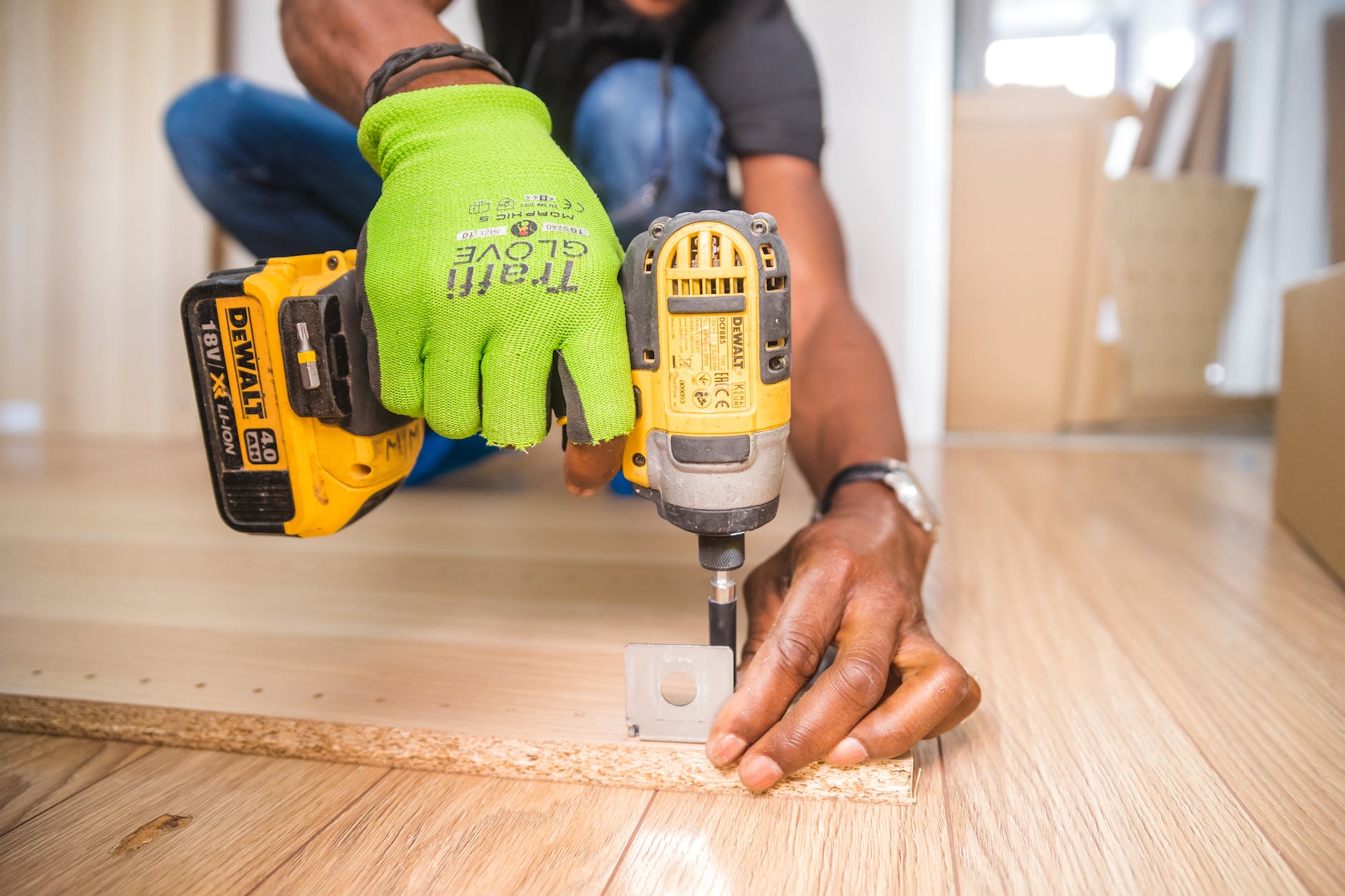 person using dewalt cordless impact driver on brown board